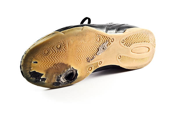 Worn out sports Shoe with hole on bottom, white background.