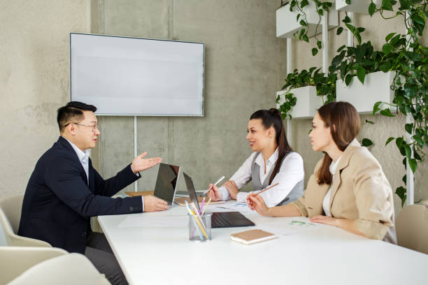 różni koledzy z azji i rasy kaukaskiej współpracują ze sobą, omawiają nowe rozwiązania w zakresie wyszukiwania projektów - speech recruitment technology young adult zdjęcia i obrazy z banku zdjęć