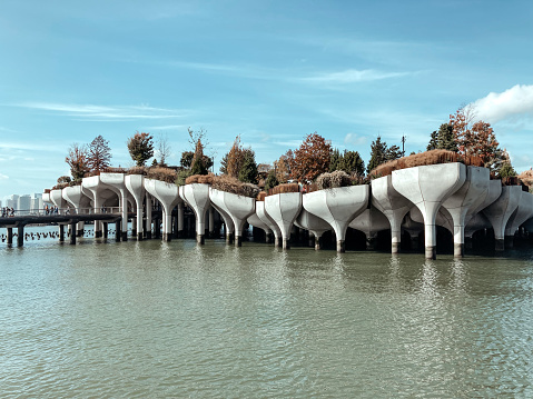 a futuristic island in the hudson river made of concrete tulips