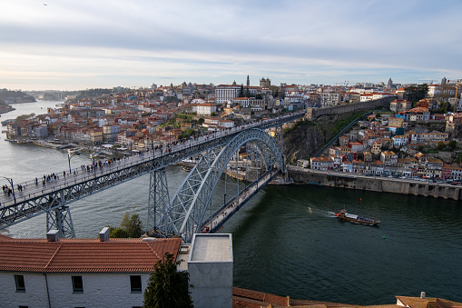 Image from the top of the Dom Luis I bridge in Porto with the city in the background under a cloudy spring sky.