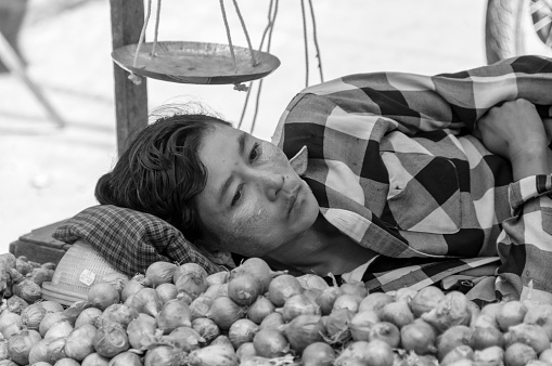 Yangoon, Myanmar - oct 30, 2012 : in a farmer's market in Yangon a young greengrocer rests on a bed of garlic