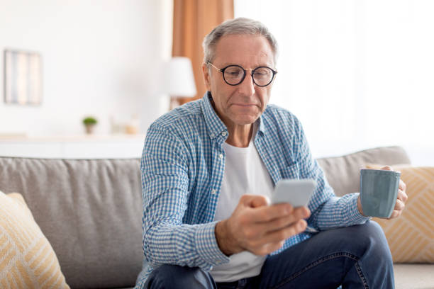 istock Portrait of mature man using smartphone drinking coffee 1477233892