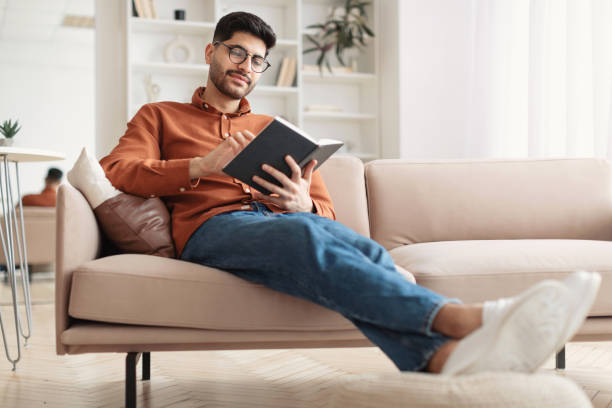 istock Smiling Arab man in glasses reading paper book 1477233965