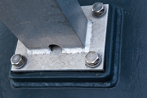 A welded aluminum post welded to the plate and bolted to the deck, close-up.