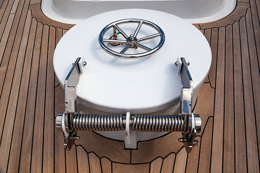 Waterproof closed hatch with stainless steel hinges on the teak deck of a luxury yacht. Water tight door on a ship.