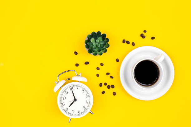 istock Alarm clock, cup of coffee and coffee beans on a yellow background, flat lay. 1477238949