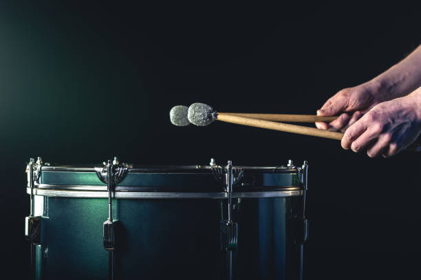 istock A man plays a musical percussion instrument with sticks on a dark background. 1477239634