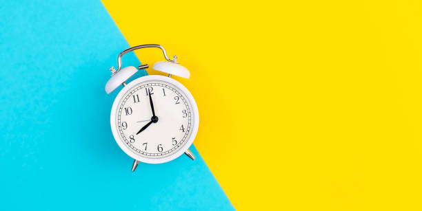 istock White alarm clock on a blue and yellow background, flat lay. 1477240411