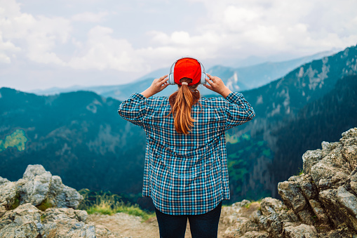 Woman in headphones listening music in nature and at the mountain, female tourist with long blond hair relax after walking enjoy journey trip, copy space