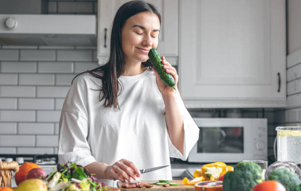 istock Attractive young woman cutting vegetables for salad in the kitchen. 1477241181
