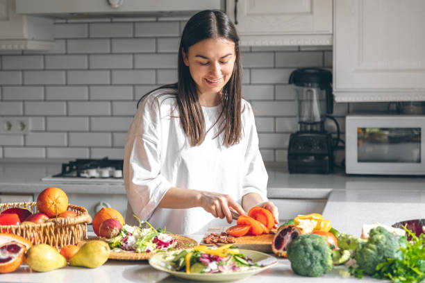 istock Attractive young woman cutting vegetables for salad in the kitchen. 1477241203