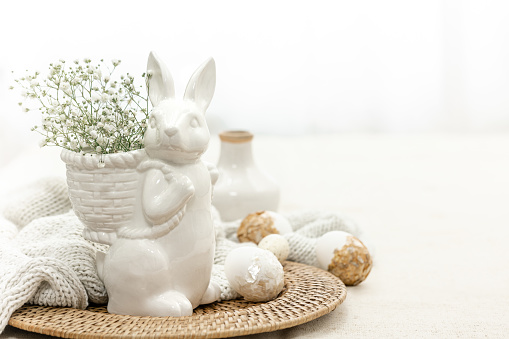 Easter composition with ceramic hare and eggs on a light background, Easter home decor, copy space.