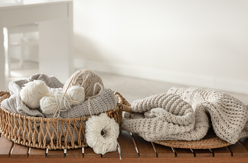 Basket with threads for knitting on a wooden bench in the interior of the room, the concept of knitting.