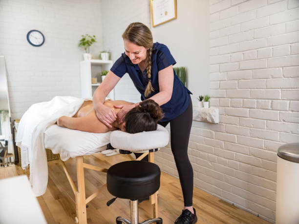 Female massage therapist treating female patient stock photo
