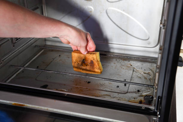 istock Female hand with sponge and detergent cleaning the kitchen oven from burnt drops 1477245810