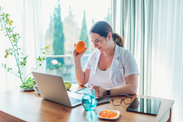 istock Nutritionist having video call with patient and holding orange 1477247862