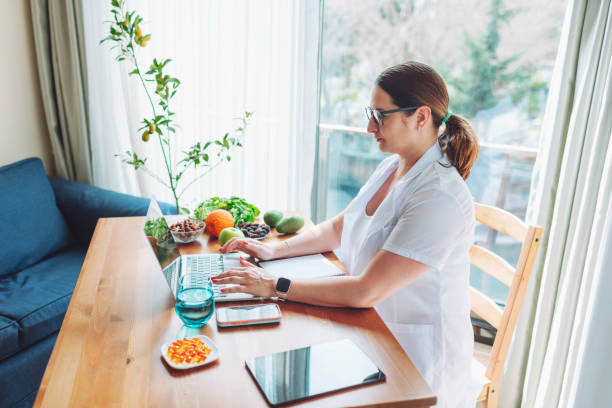 istock Nutritionist female doctor working using laptop writing diet plan 1477248107
