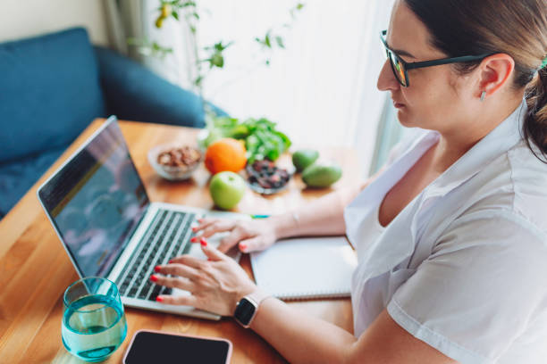 istock Nutritionist female doctor working using laptop writing diet plan 1477248655