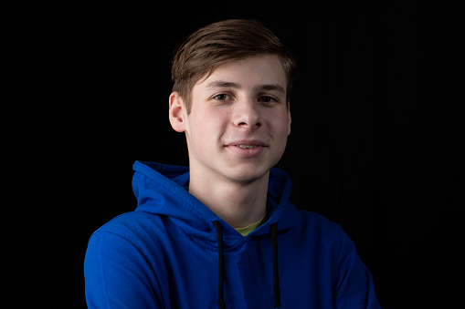 Portrait of a smiling teenager on a black background. Portrait of a young man.
