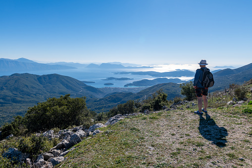 A tourist enjoying the panoramic view from a mountain top on a hiking holiday.