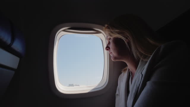 A young woman looks out the window of the plane, which begins to accelerate along the runway. Start of the journey