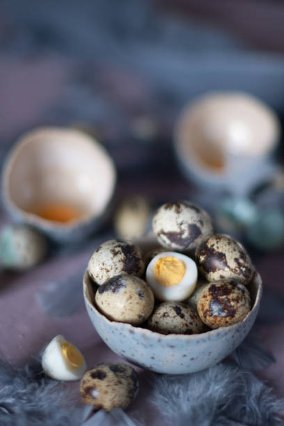istock quail eggs in ceramic vases, gray feathers on the table, easter still life, 1477255510