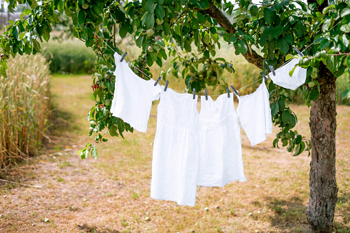 Snow-white wet clothes hanging drying on a string in the garden. Hypoallergenic Safe Bleach for White Baby Clothes