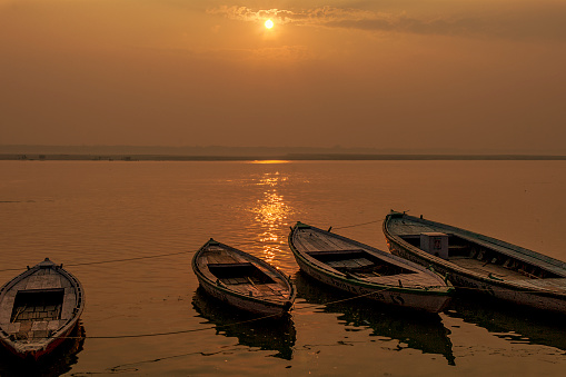 Peaceful sunrise, sunset warm landscape of river bank with boats. Ganga river bank. Varanasi, India.