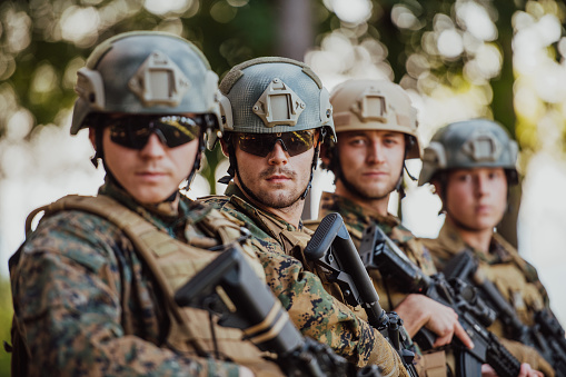 Soldier fighters standing together with guns. Group portrait of US army elite members, private military company servicemen, anti terrorist squad.