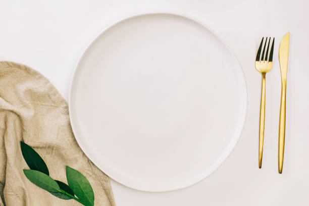istock Empty plate and golden cutlery on the white table. Minimalist table setting 1477265625