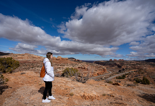 Young woman standing on top of the mountain enjoying beautiful scenery . Potash Road or the Lower Colorado Scenic Byway, Moab, Utah,USA