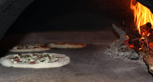istock three pizzas being cooked in a wood oven. 1477267737