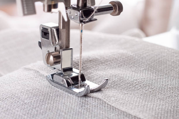 istock Modern sewing machine presser foot with linen fabric and thread, closeup 1477270390