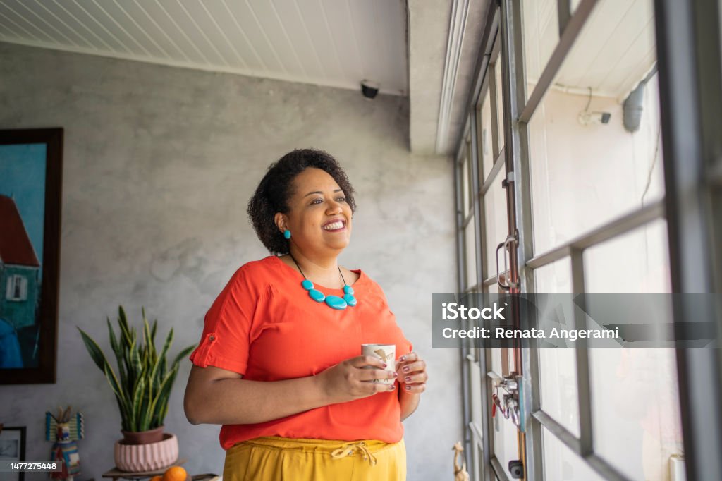 Black mature woman near the window drinking tea Digital Detox Stock Photo