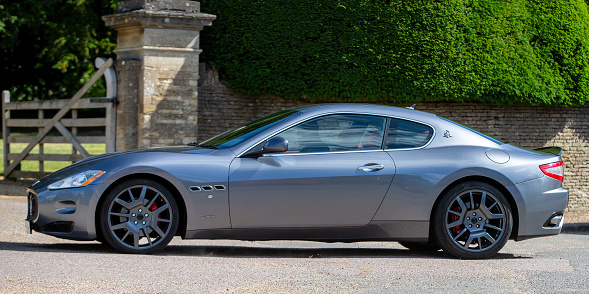 Turvey, Bedfordshire, UK - June 12th 2022. 2007 4244 cc MASERATI coupe 4200 GT  car driving through an English village