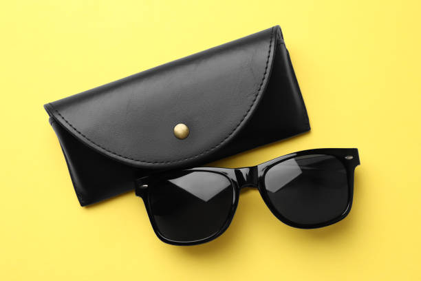 istock Stylish sunglasses and black leather case on yellow background, flat lay 1477280246