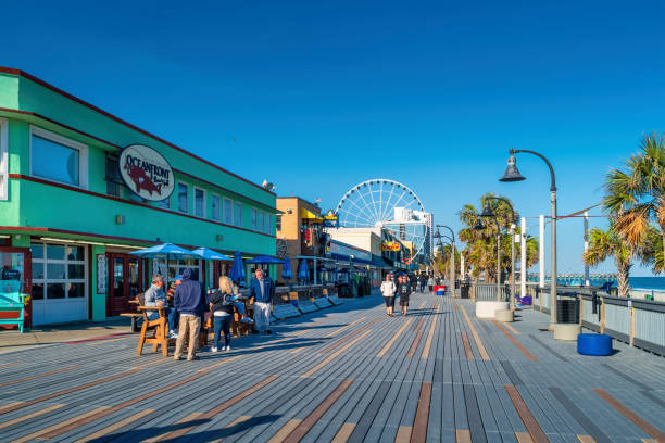 People enjoy the Myrtle Beach Boardwalk in Myrtle Beach, South Carolina, USA on a sunny day.
