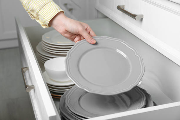 istock Woman taking grey plate from open drawer in kitchen, closeup 1477282922