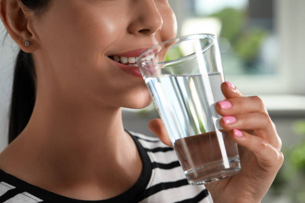 istock Young woman drinking water indoors, closeup. Refreshing drink 1477283363