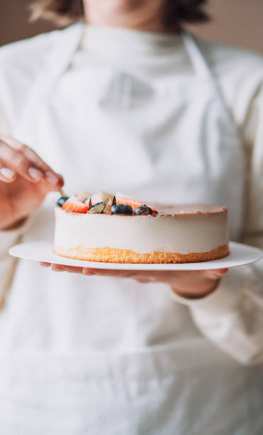 istock Lady confectioner in white uniform holding bird's milk cake 1477290803