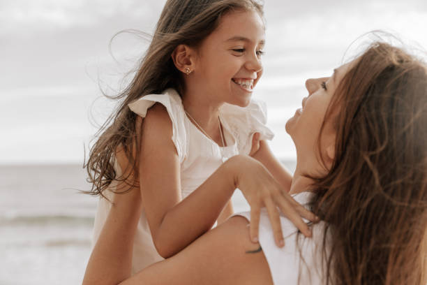 istock Delighted mother hugging smiling daughter near ocean 1477291501