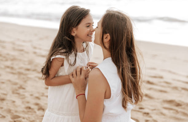 istock Mother and daughter touching noses on beach 1477291503