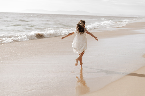Carefree girl running near waving sea