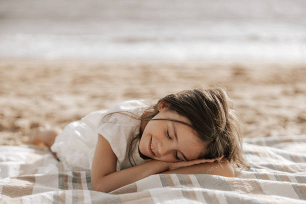 istock Smiling kid with closed eyes relaxing on sandy seashore 1477291550