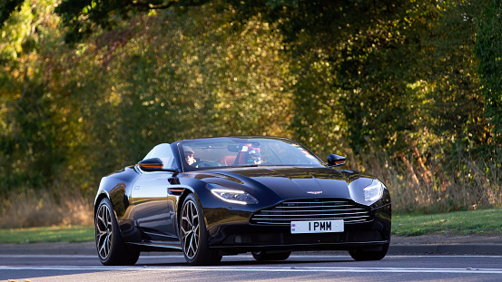 Bicester,Oxon,UK - Oct 9th 2022. 2019 black Aston Martin DB11 car driving on an English country road