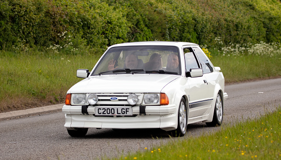 Aylesbury,Bucks,UK - May 15th 2022. 1986 white Ford Escort classic car driving on an English country road