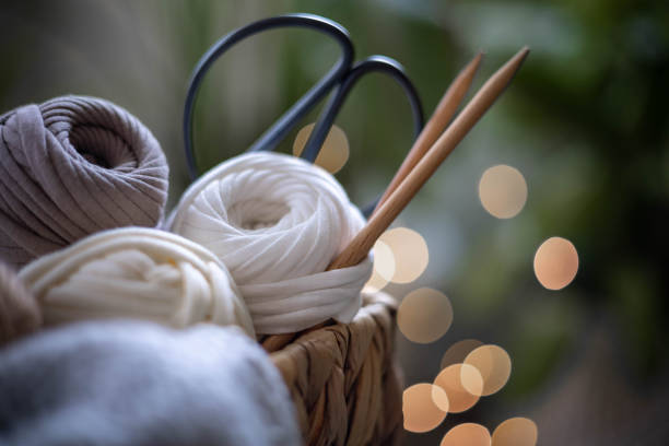 Cozy homely atmosphere. Female hobby knitting. Yarn in neutral shades in a basket woven from natural jute. stock photo