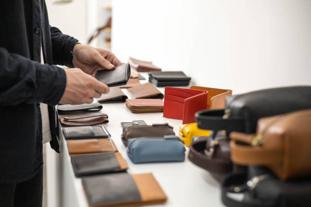 istock Craftsman hands laying out leatherwork on wooden showcase at leather workshop. Handwork accessories 1477301890