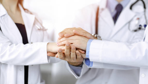 istock Group of modern doctors joining hands as a circle. Teamwork in medicine during Coronavirus pandemic, covid 2019 1477307098