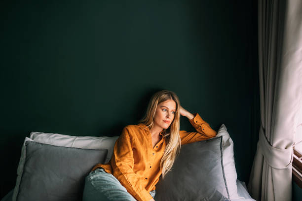 istock A Beautiful Blonde Woman Looking Away While Sitting On Her Cozy Sofa 1477307960